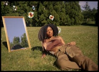 a woman laying on the grass next to a mirror