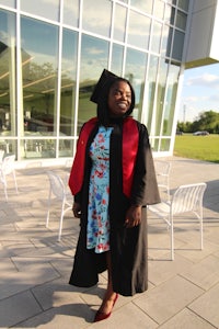 a woman in a graduation gown standing in front of a building